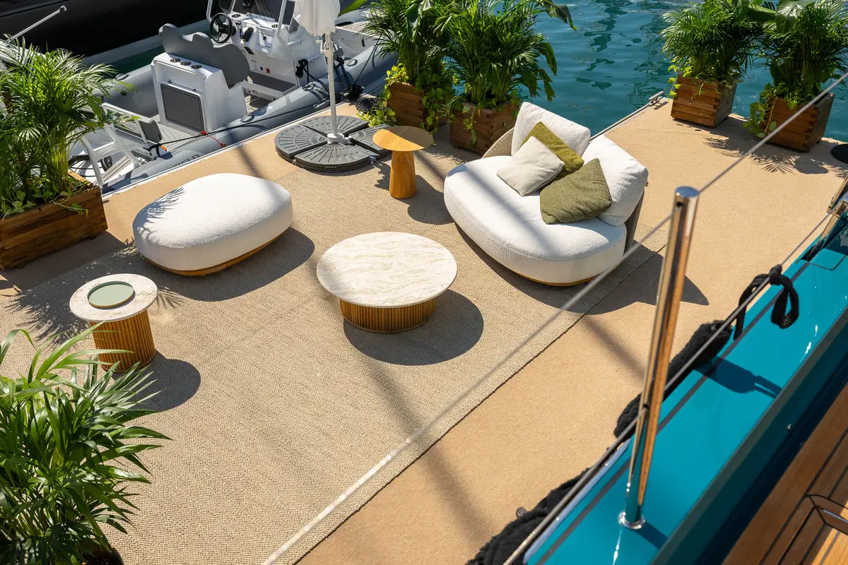 Foredeck lounge of a catamaran with sofas, side tables and plants