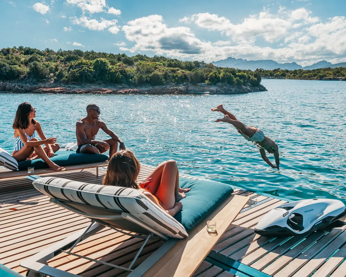 Guests relaxing on deck while one dives into the sea next to a Seabob
