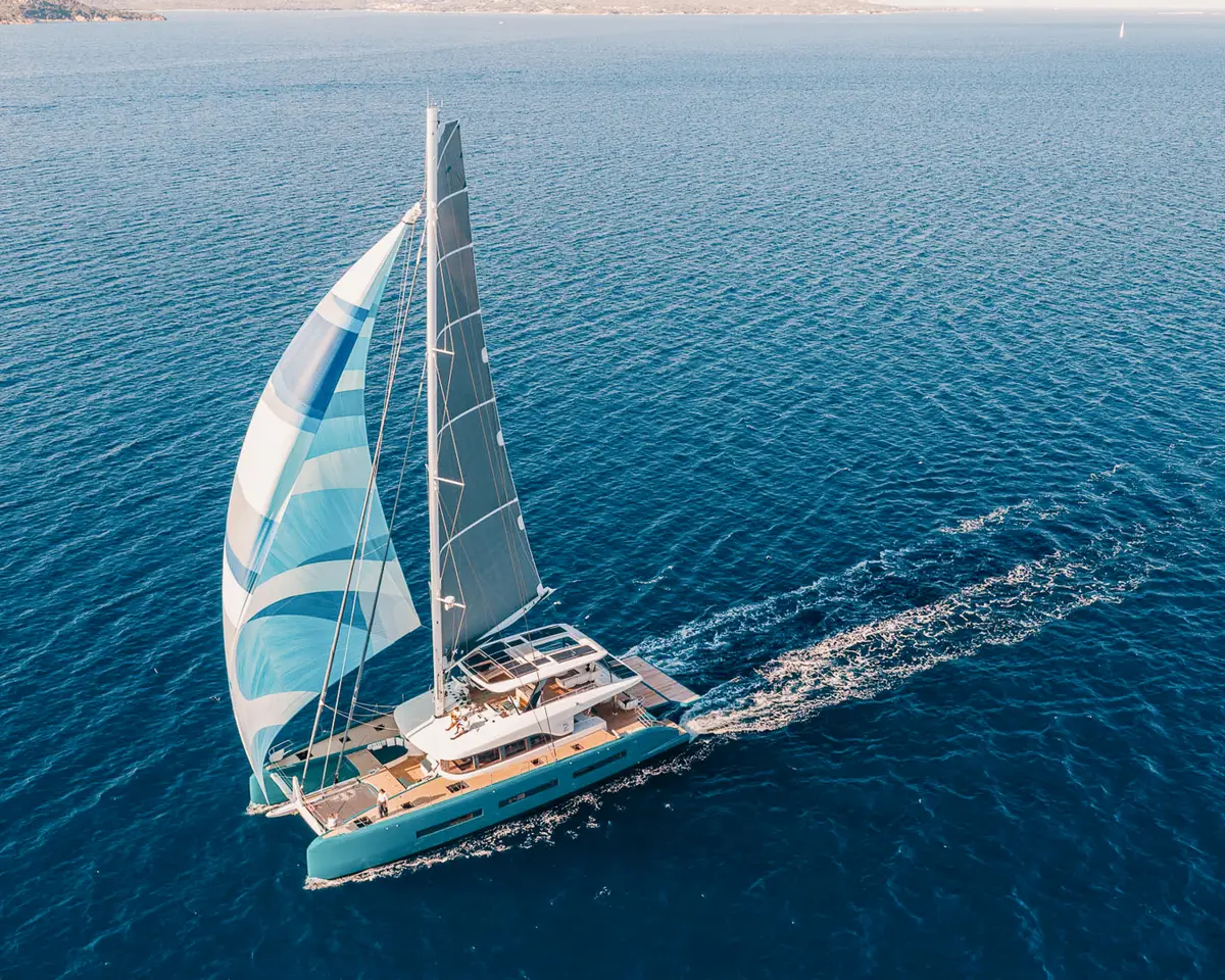 Aerial view of a luxury catamaran under full sail on deep blue water