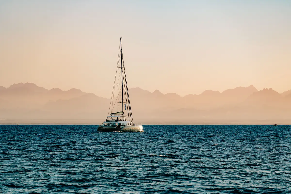 Sailing catamaran on the Red Sea at dusk with mountains on the horizon